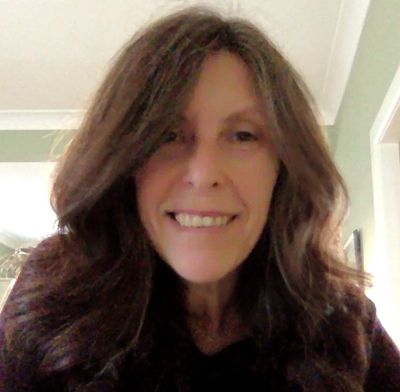 Smiling woman with long brown hair indoors.