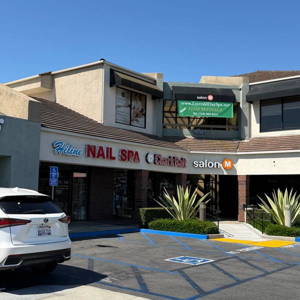 Strip mall with nail spa, chalk bar, and salon under clear blue sky.