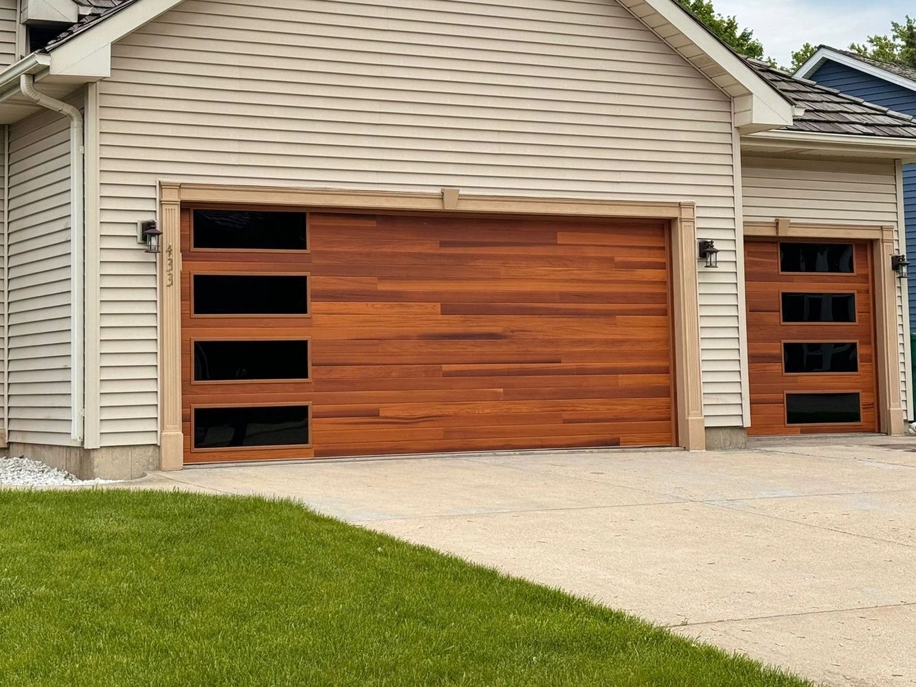 Modern house with wooden garage doors and a green lawn.