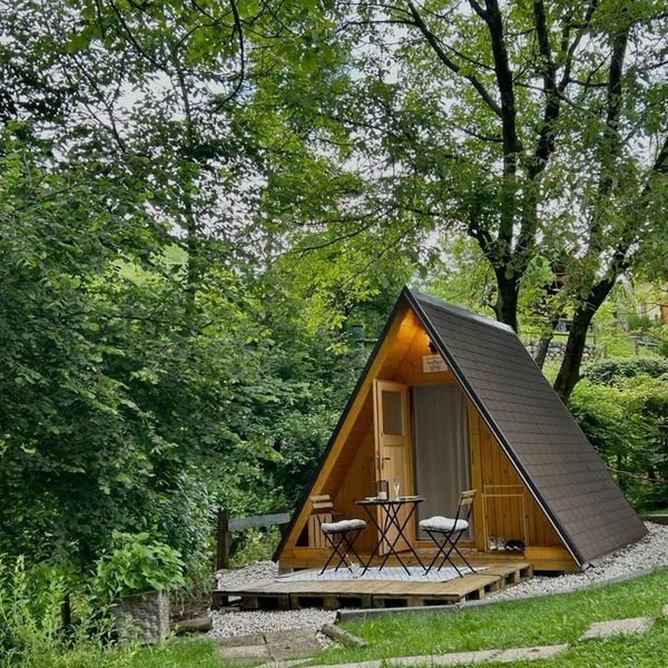 Cozy A-frame cabin with outdoor seating surrounded by lush greenery.