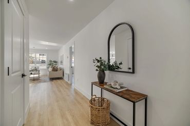 Minimalist hallway with wooden console table and arched mirror.