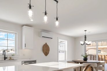 Bright modern kitchen with white cabinetry and wooden stools at the island.