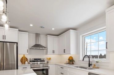 Bright modern kitchen with white cabinets and stainless steel appliances.