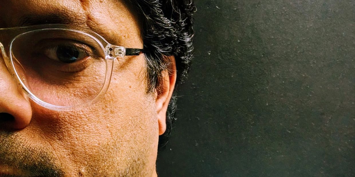 Close-up portrait of a man wearing glasses and a light blue shirt.