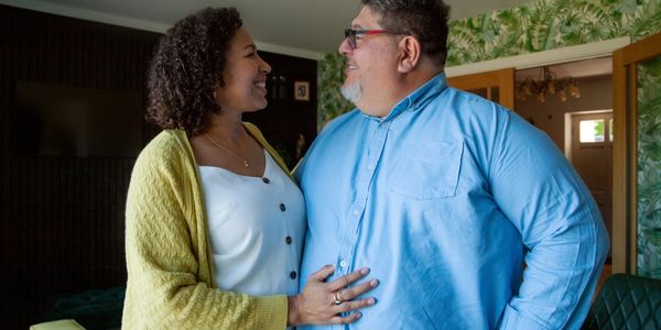 A couple smiling and embracing each other indoors.