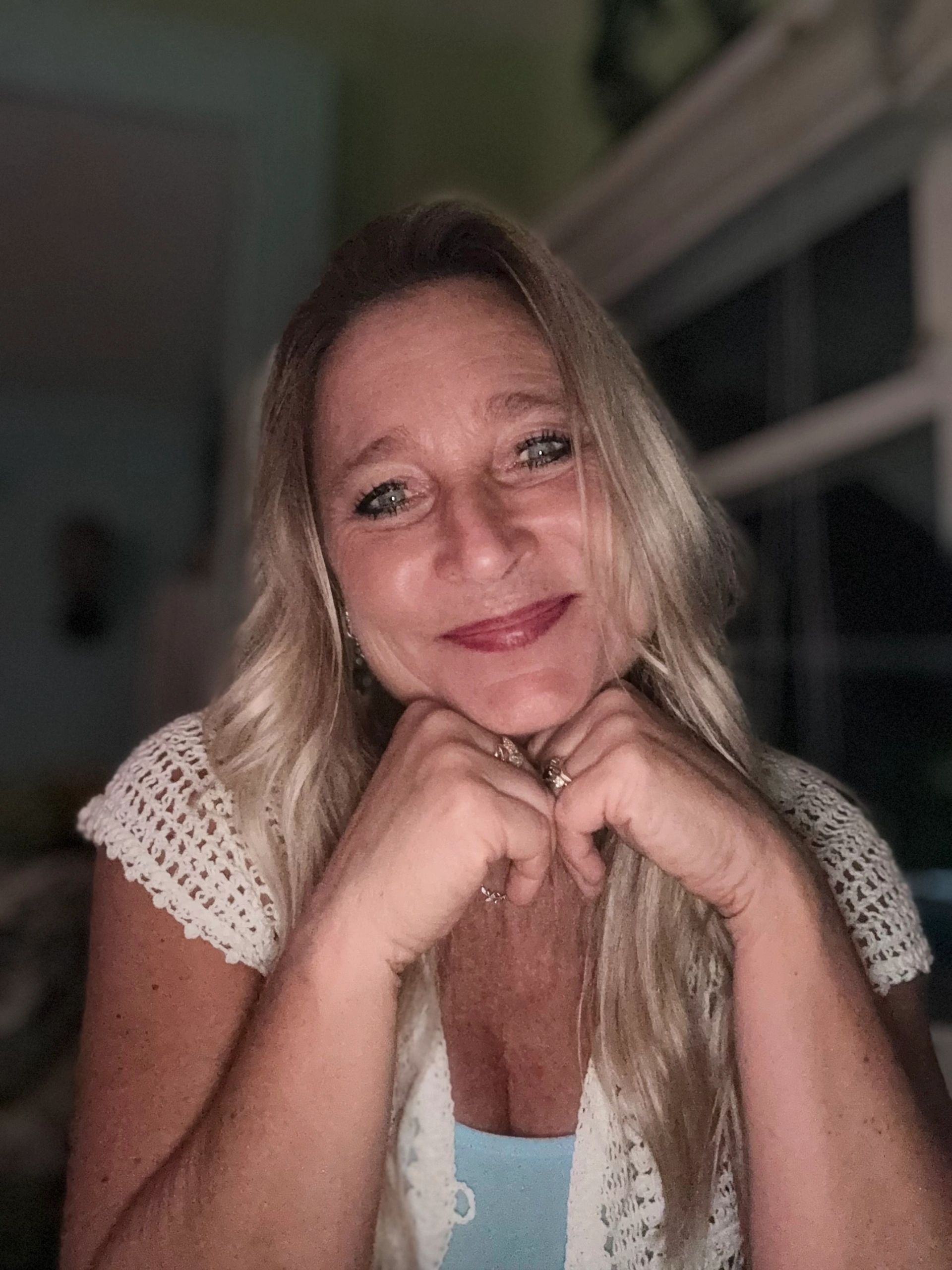 Smiling woman with blonde hair resting her chin on her hands.