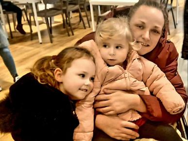 A woman with two young children, all bundled up warmly indoors.