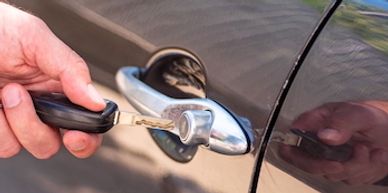 Man putting remote key in car door lock.