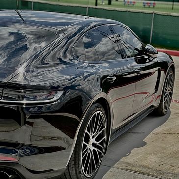 Sleek black luxury car parked outdoors with reflective shiny surface.