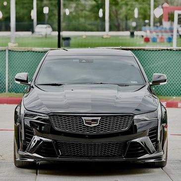 Front view of a sleek black Cadillac car parked outdoors.