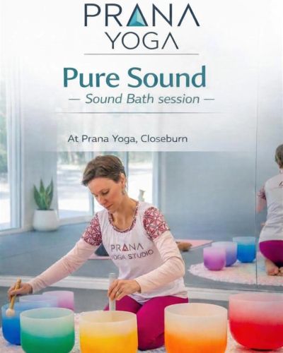 Woman at Prana Yoga playing colorful sound bowls during a sound bath session.