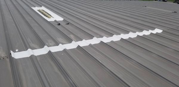 Leaking skylight and failing metal seam have been sealed with a high solid silicone roof sealant.