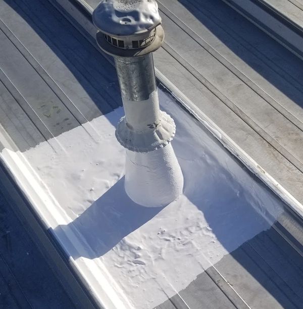 high solids silicone roof coating has been applied to the roof stacks on this metal roof.
