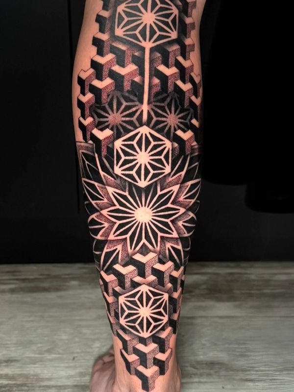 Geometric blackwork tattoo with intricate hexagonal and floral patterns on a calf.