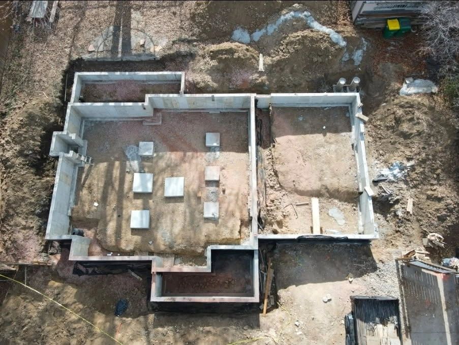 Aerial view of a house foundation under construction with defined rooms and concrete blocks.