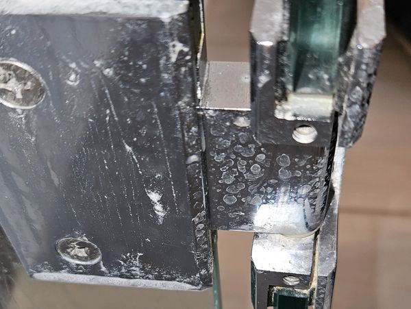 Close-up of a metallic hinge with water spots.