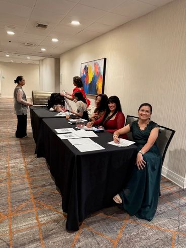 Women seated at a table with documents in a conference room.