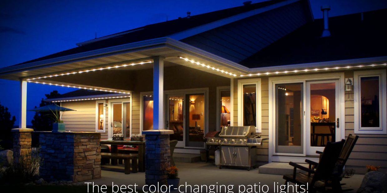 Cozy illuminated patio with string lights and outdoor grill at night.