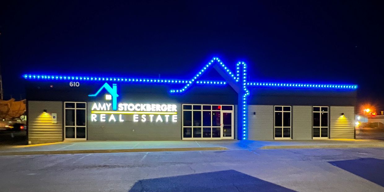 Amy Stockberger Real Estate office illuminated with blue lights at night.