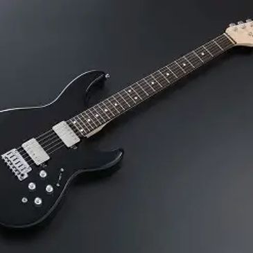 A sleek black electric guitar with silver hardware on a dark surface.