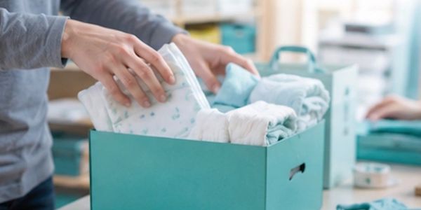 Person packing clothes in a teal box.