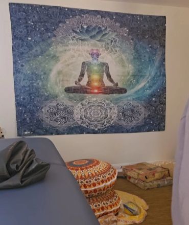Meditative room with chakra tapestry and cushions.