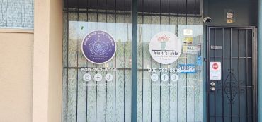 Front entrance of Trinni's Table with business signs on glass doors.