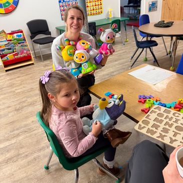 A young girl and a woman with colorful toys in a classroom setting.