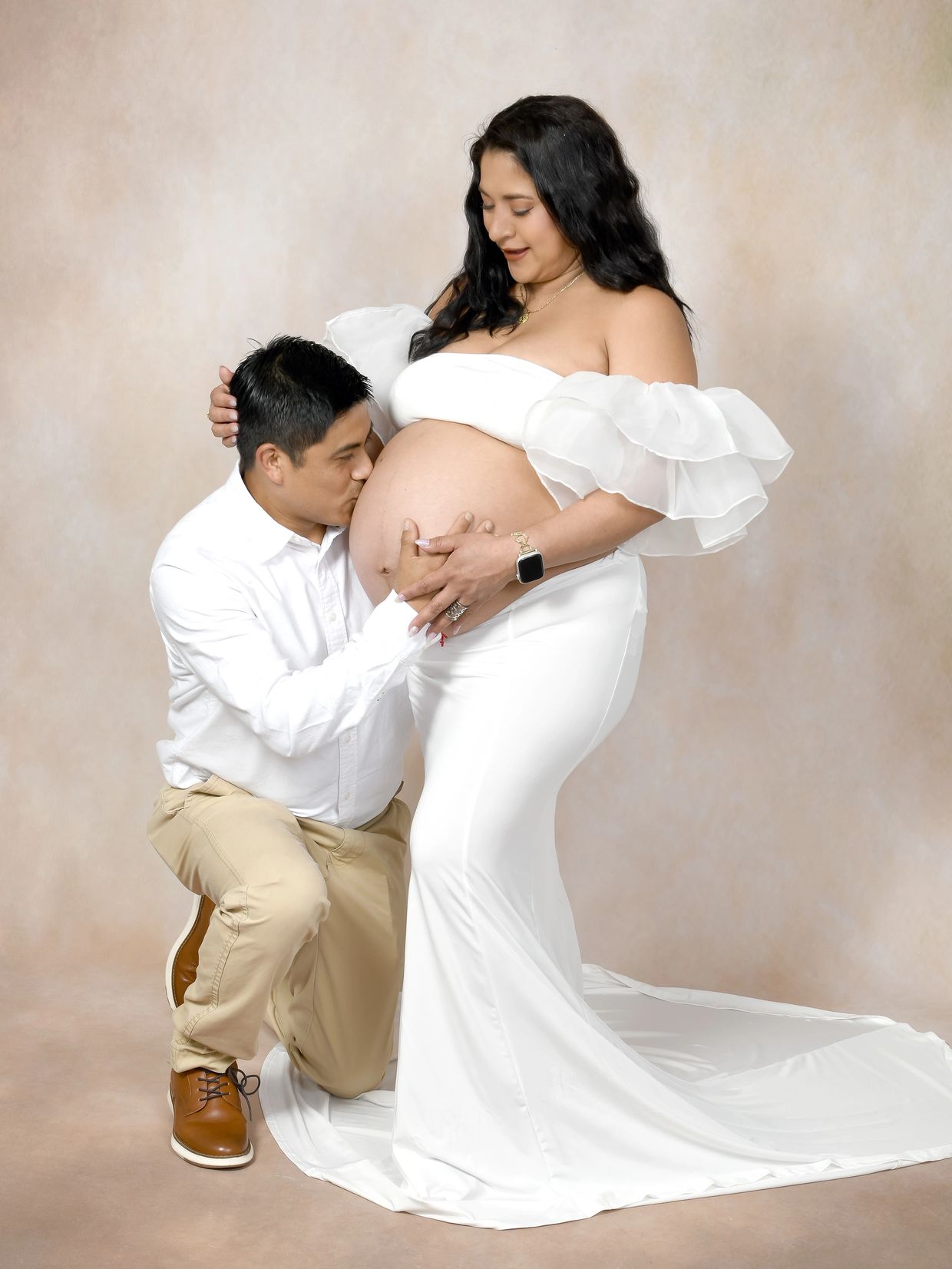 Man kissing pregnant woman's belly lovingly.