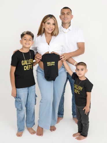 Family photo with a mother holding a baby onesie, father and two boys.