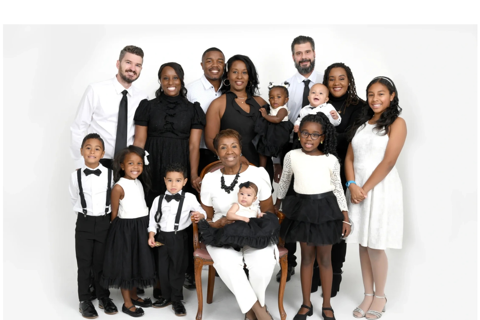 Large multigenerational family portrait with coordinated black and white outfits.