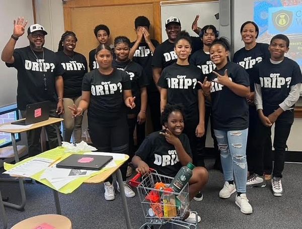 Kids at a financial literacy camp wear DRIP shirts, learning investing and wealth-building skills.