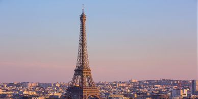 The Eiffel Tower in Paris, France, standing tall against a blue sky and scattered clouds.