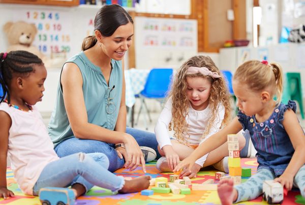Teacher and kids looking happy while doing activity at kindergarten or pre-school.