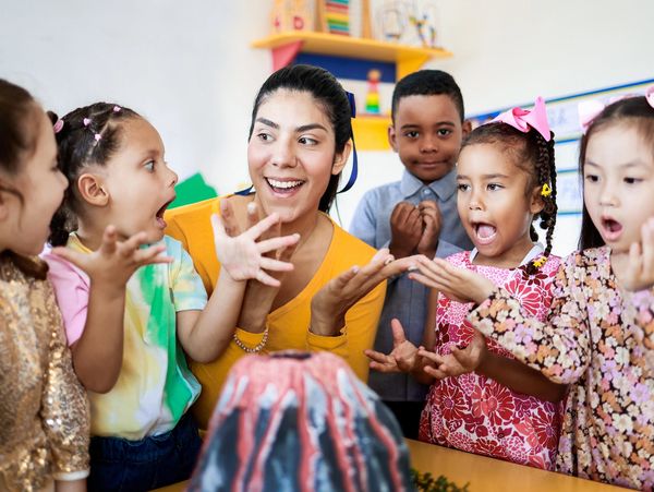Teacher and group of children learning about volcanos at science kindergarten project