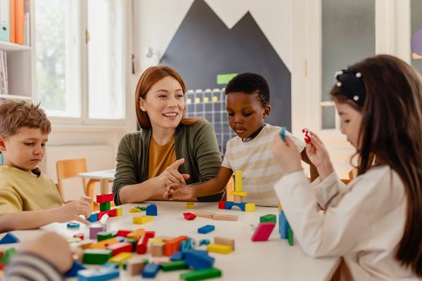 Diverse preschool children play with colorful building blocks at a classroom table
