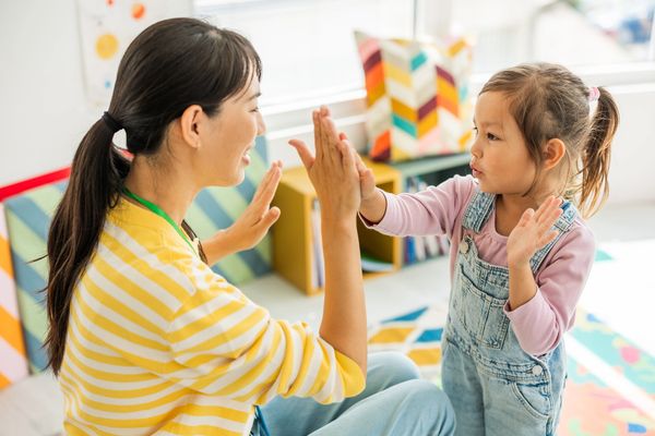 Preschool teacher with children playing at kindergarten
