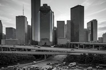 Black and white city skyline with highways and scattered vehicles in foreground.