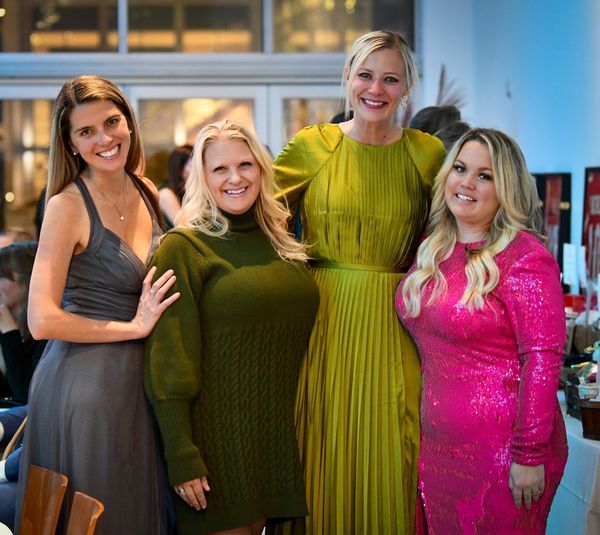 4 women in brightly colored dresses smile and pose for a photo,