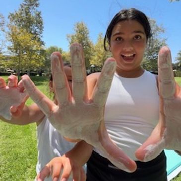 Excited girl showing chalk-covered hands outdoors.