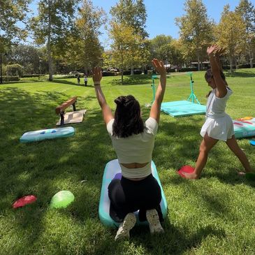 Two women exercising outdoors on grass.