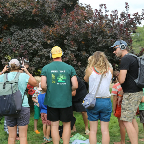 Group of people listening to nature sounds with headphones in a park.
