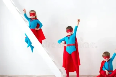 Three kids in superhero costumes posing confidently indoors.