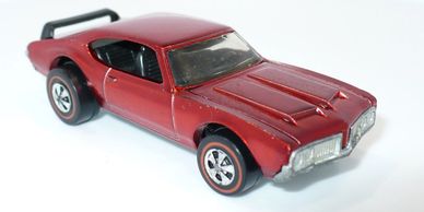 Red toy muscle car with black spoiler and detailed design.
