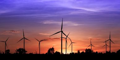 Wind turbines against a sunset, symbolizing innovation and efficient use of sustainable energy.