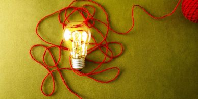 Glowing bulb with red thread, illustrating interconnected ideas and innovative online consulting.