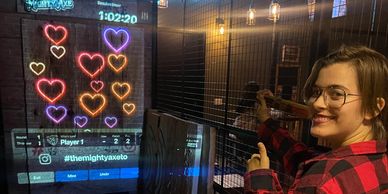 An employee at the mighty axe playing an axe throwing game for lovers