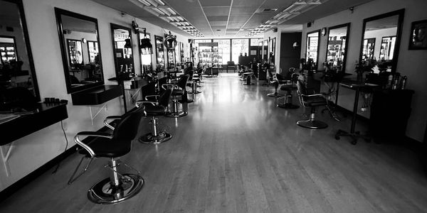 Empty black and white barbershop with multiple chairs and mirrors.