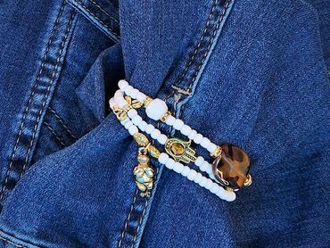 White beaded bracelet with gold accents and a brown stone and charms