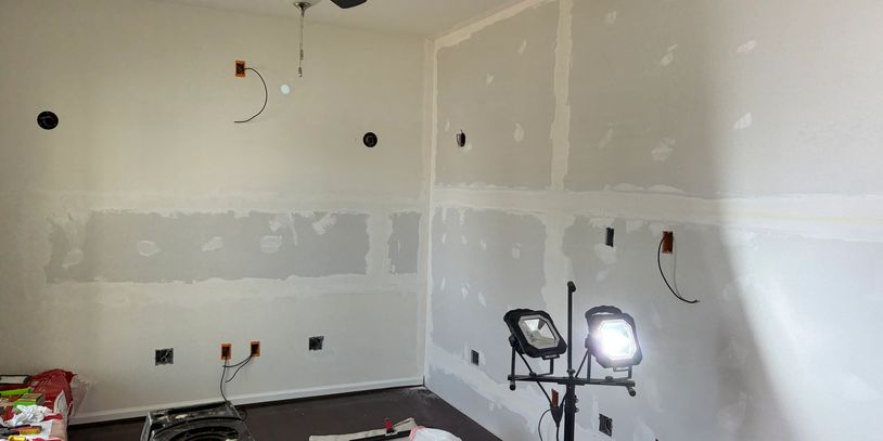 Room under renovation with drywall and work lights.